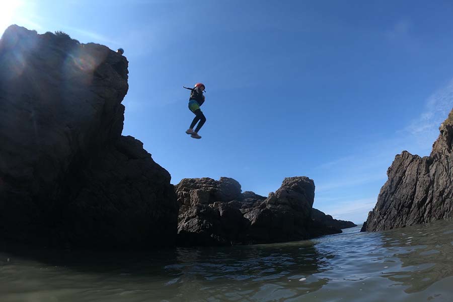 Coasteering group leaping into the sea at Croyde Bay, North Devon