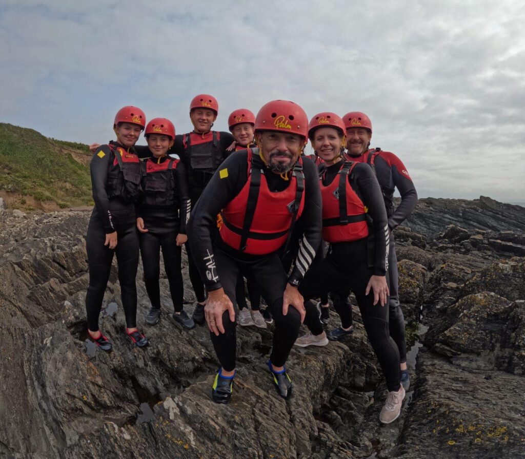 Scrambling over rocky cliffs at Croyde Bay during coasteering adventure