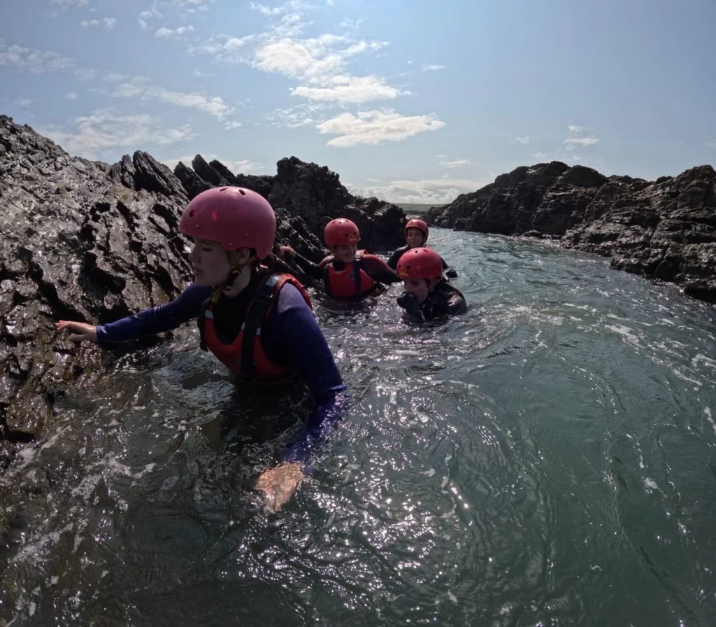 Family coasteering through tidal pools at Croyde Bay, North Devon